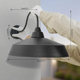 Black pendant light with measurements being held by a person against a gray wall.