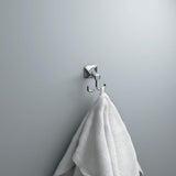 Chrome wall hook with a white towel on a gray wall