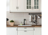 Modern kitchen with white cabinets, wooden countertop, and tiled backsplash.